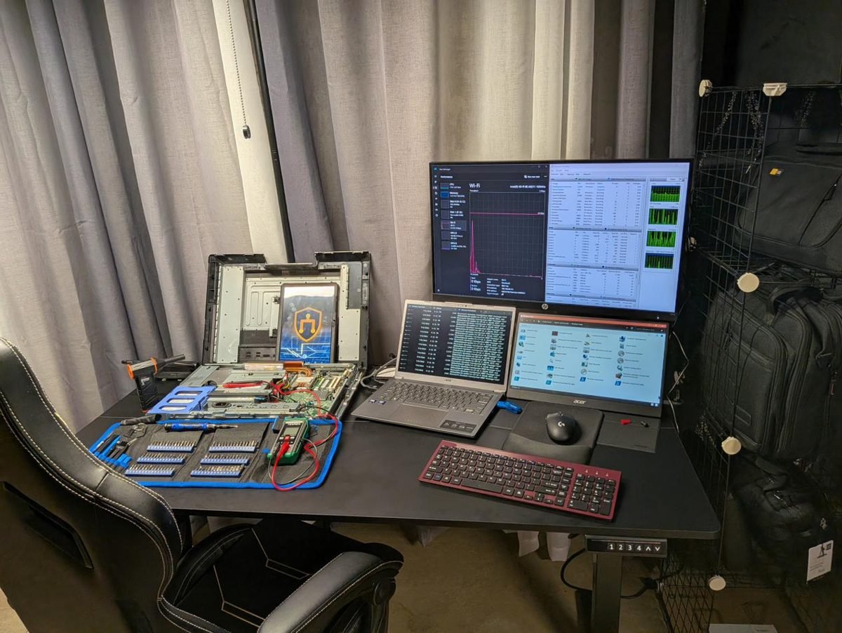 The Aurora Computer Care workshop bench with diagnostic tools, a laptop open for repair, and monitoring screens